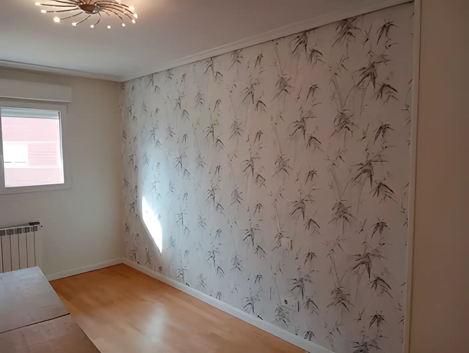 Los Pintores en Murcia colocando papel pintado en pared de acento de habitación luminosa