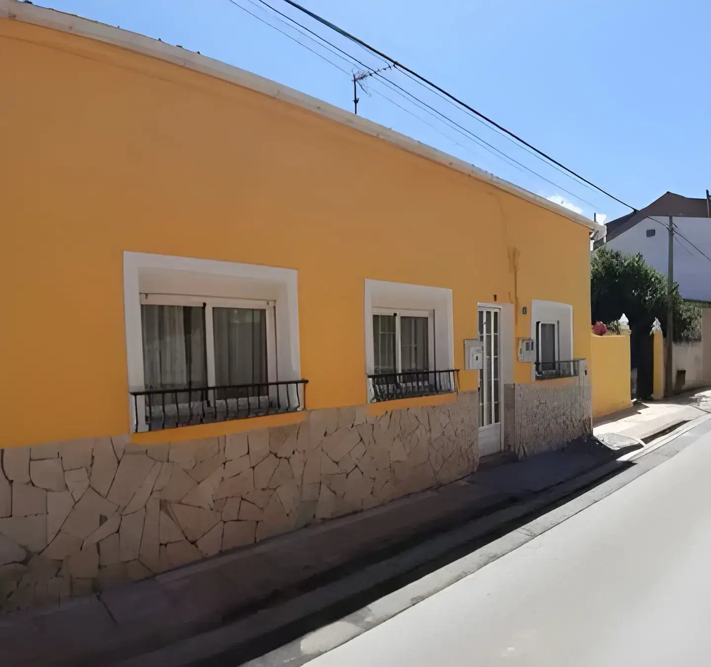 Los Pintores en Murcia Fachada de casa tradicional pintada en color amarillo con zócalo de piedra